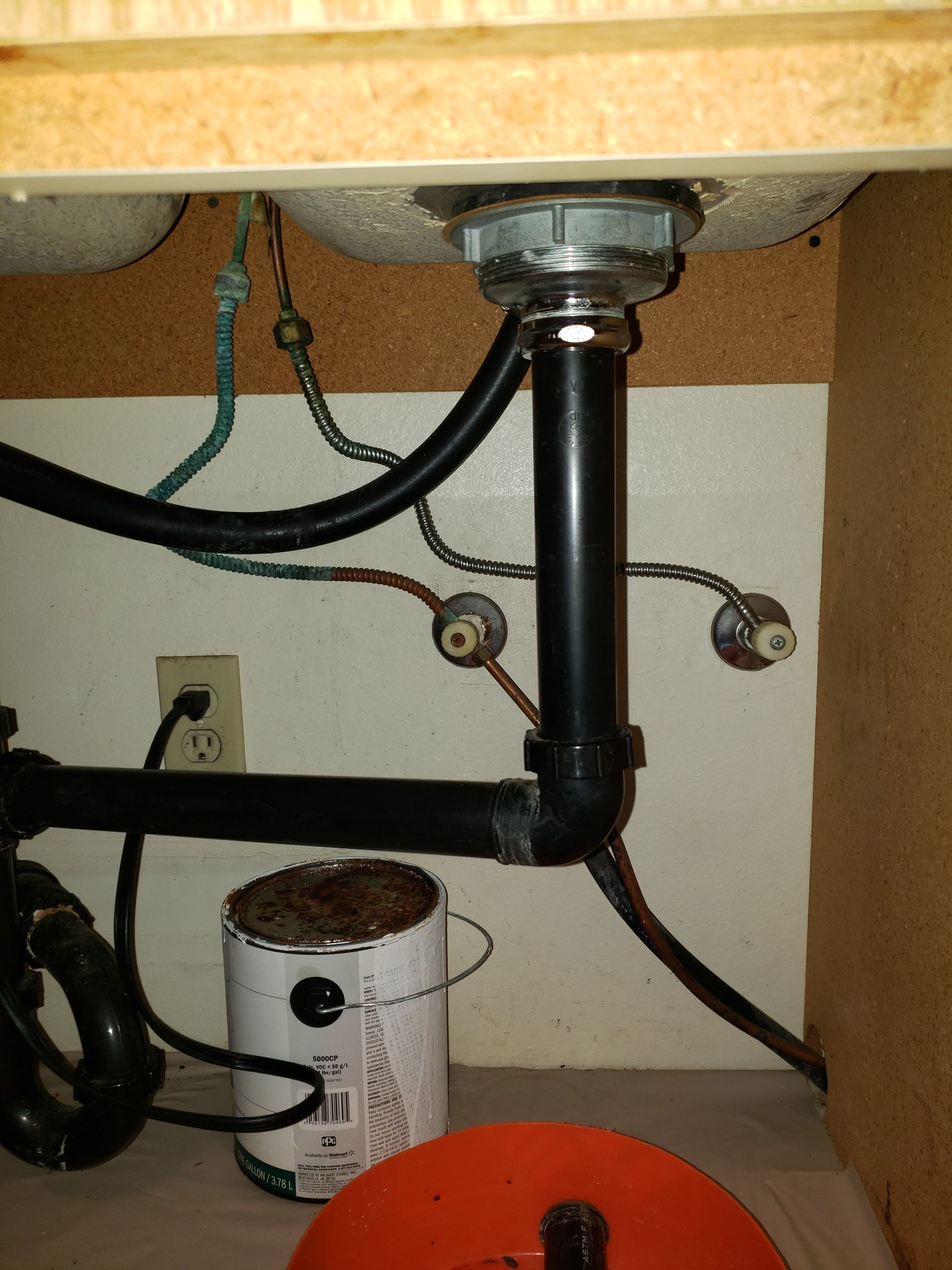 A can of paint sits under a kitchen sink