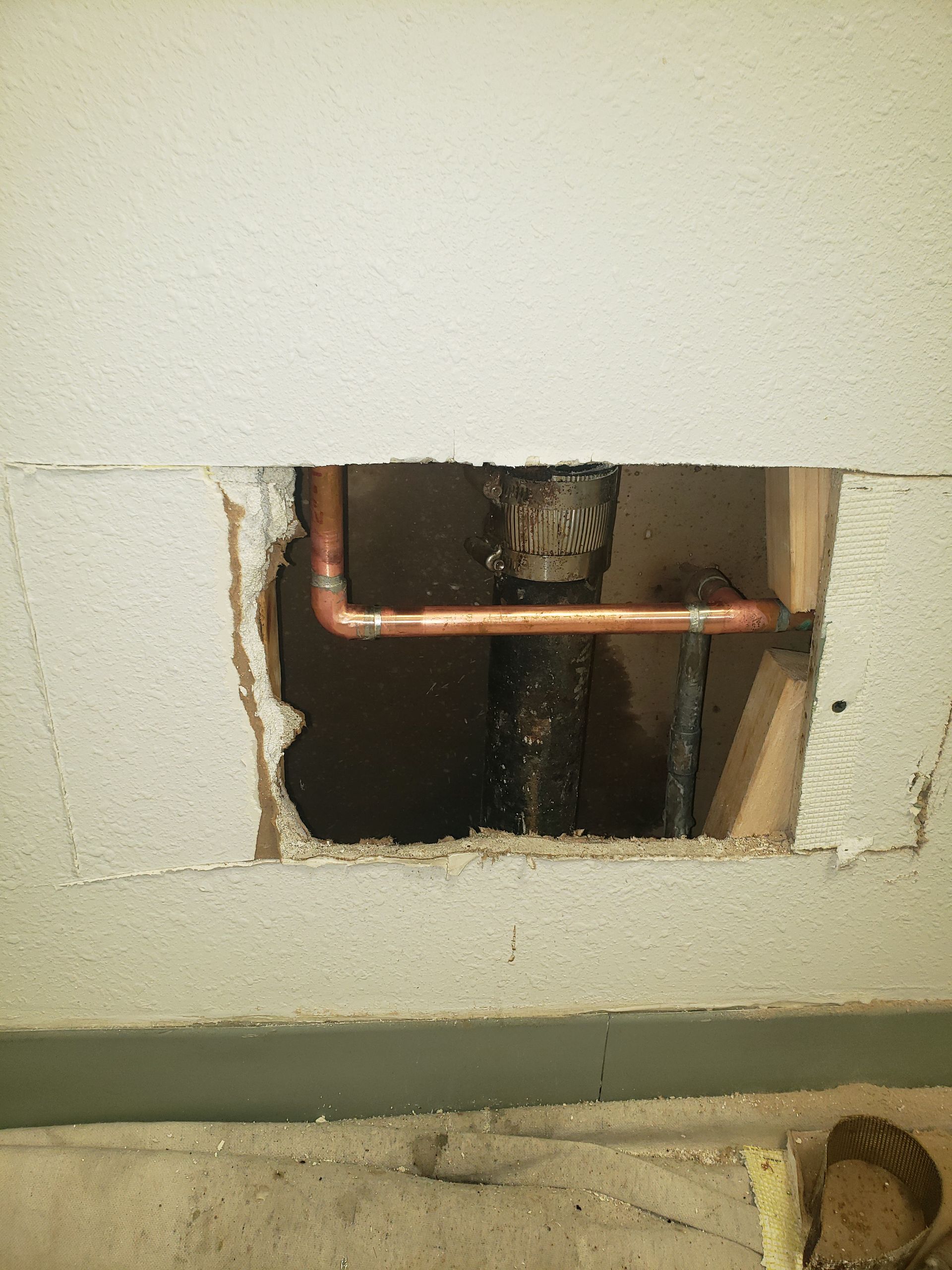 A hole in a wall with a pipe coming out of it.