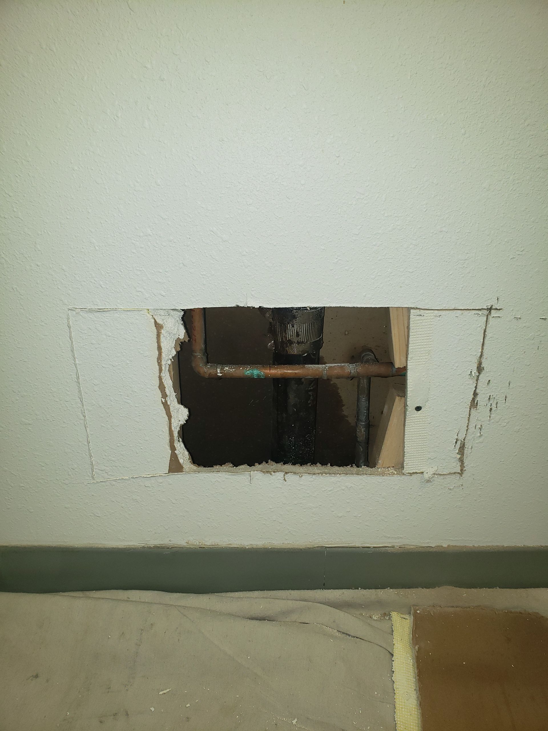 A hole in a wall with a pipe coming out of it.