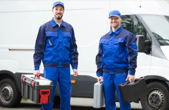 Two men are standing in front of a van holding tools.