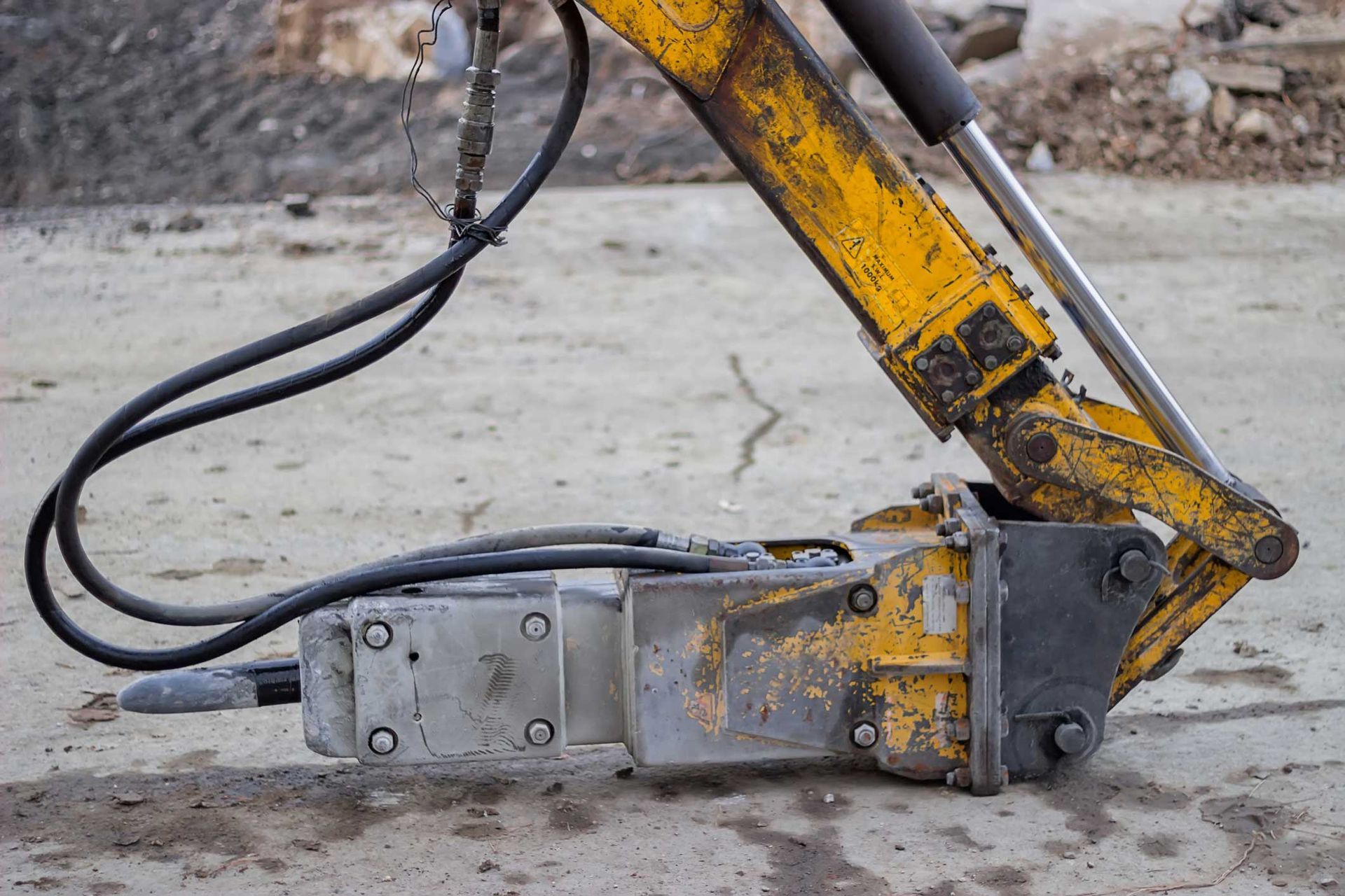 Excavator hydraulic hammer at construction site showing wear from heavy-duty industrial use. Excavator hydraulic hammer at construction site showing wear from heavy-duty industrial use.