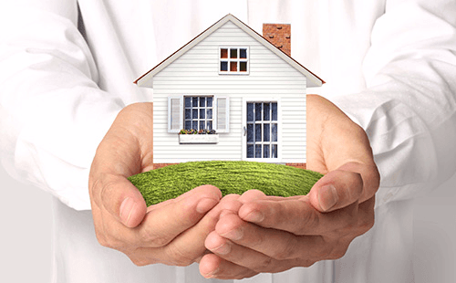 Individual holding a house in his hand 