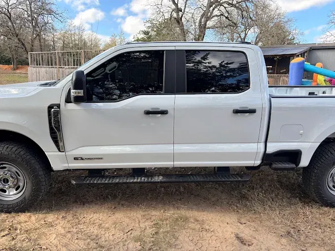Red Dodge Challenger with black racing stripes parked in a garage.