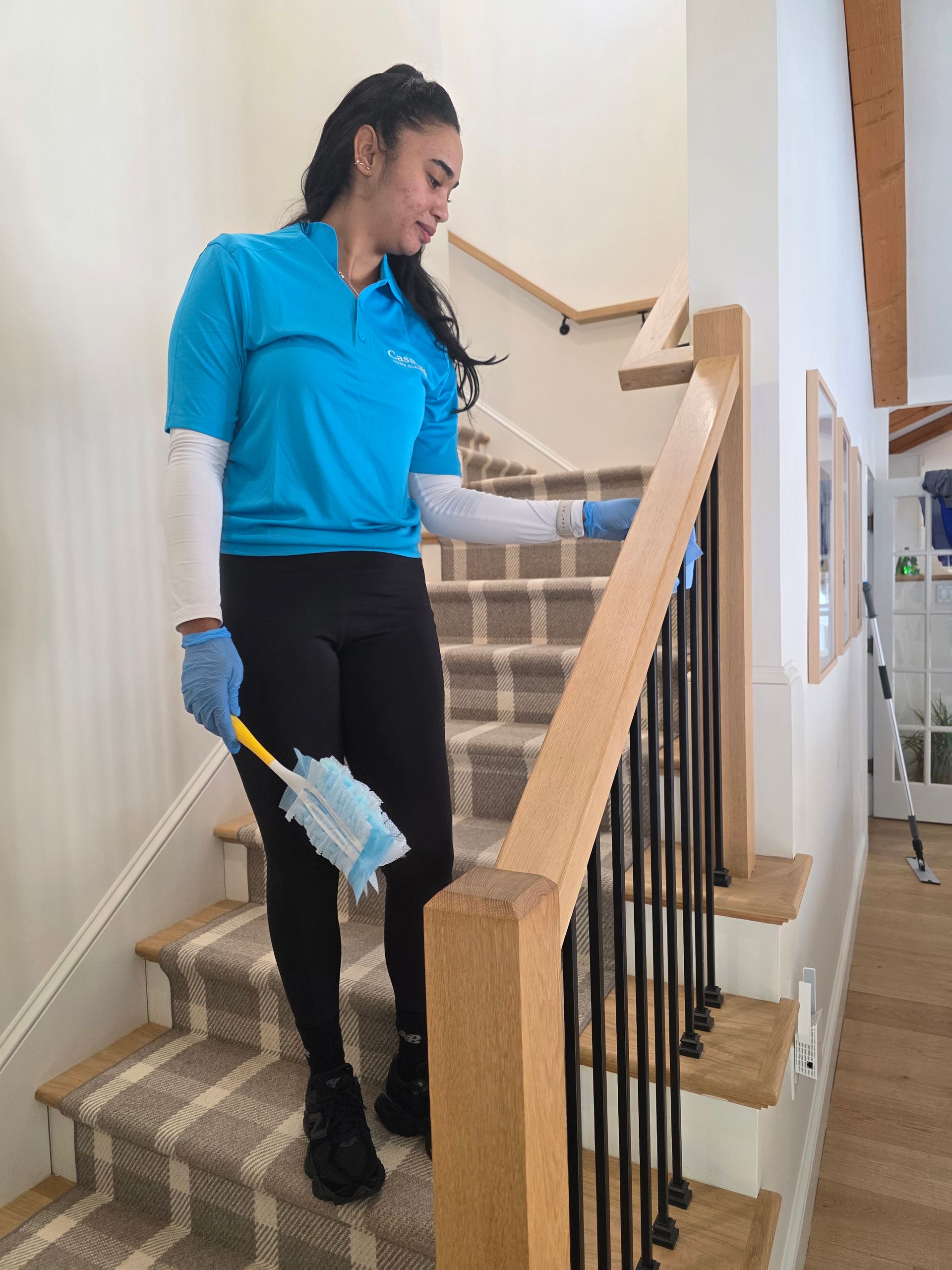 Person cleaning a stairway with a mop and bucket in a hallway