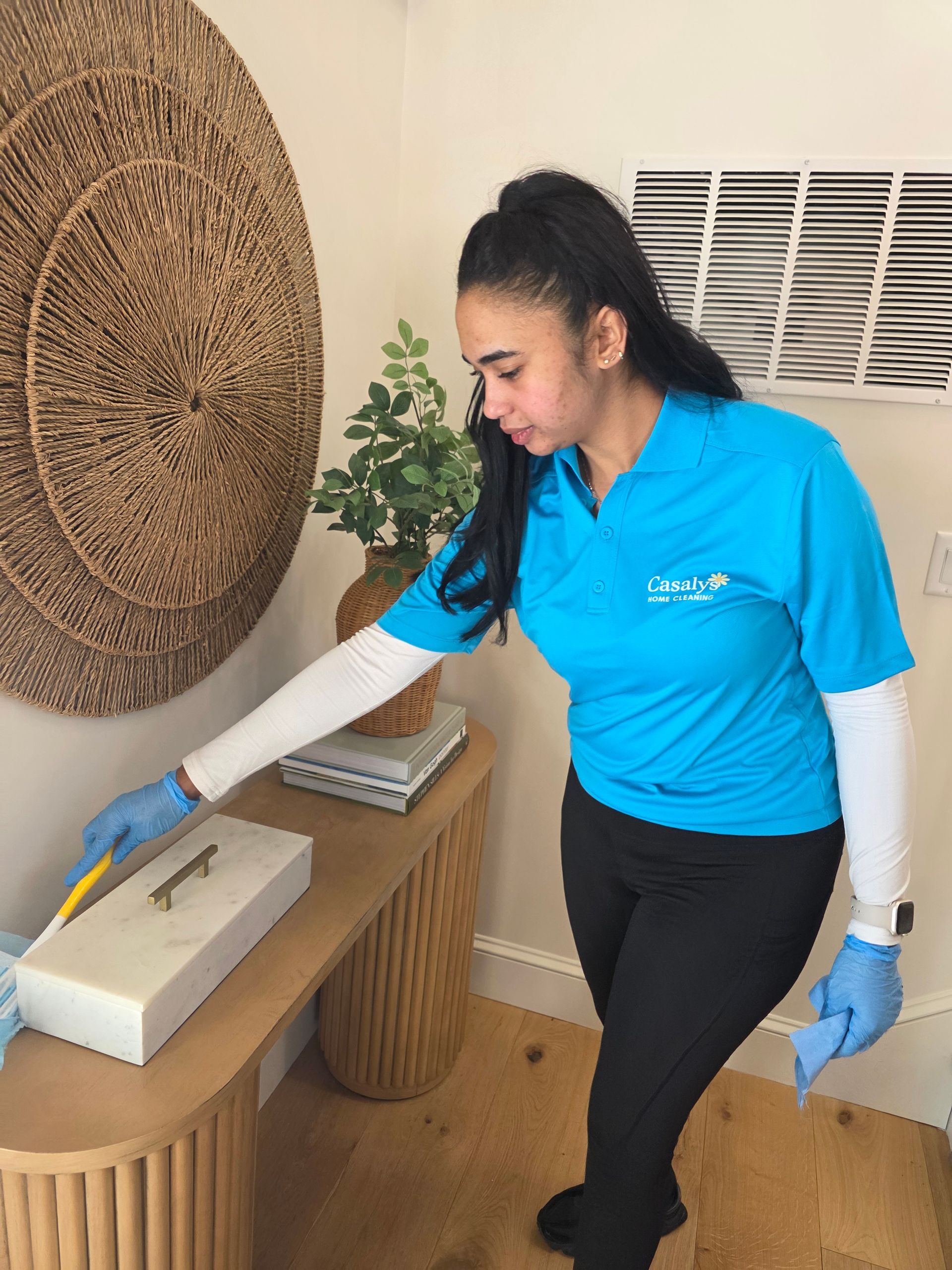 Person in blue shirt cleaning a table beside a wicker wall decor and vented wall panel.