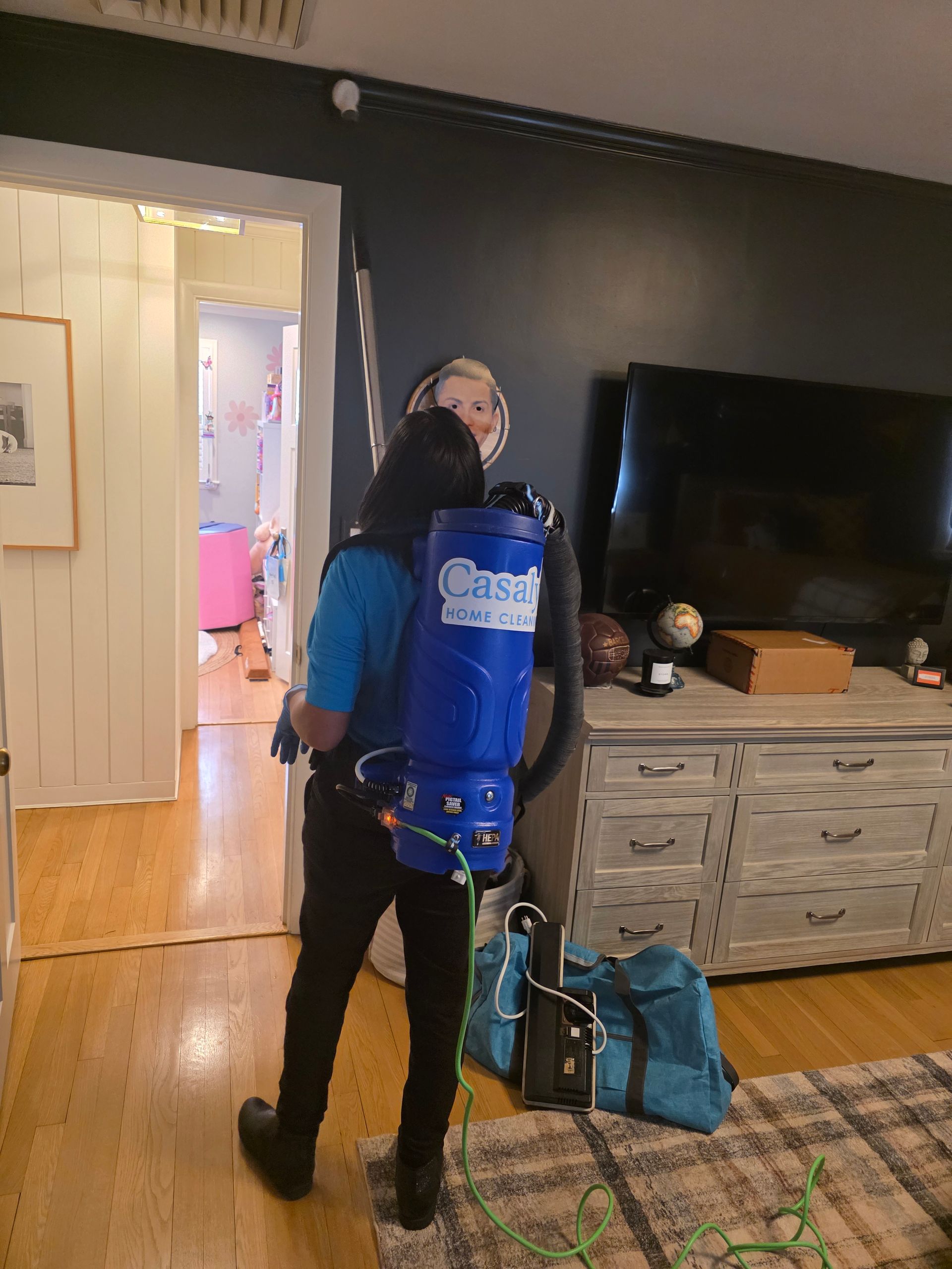 Person wearing a blue oxygen tank stands in a living room near a TV and doorway.