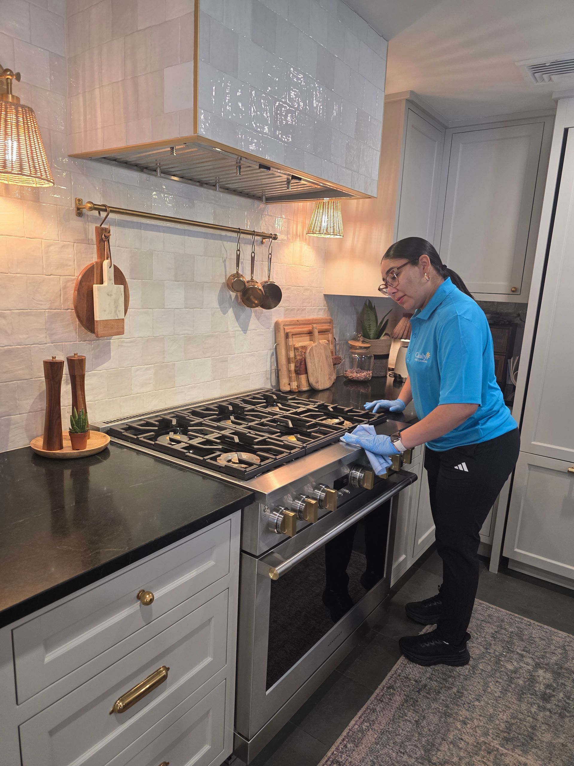Person cooking at a stainless steel stove in a bright, white kitchen