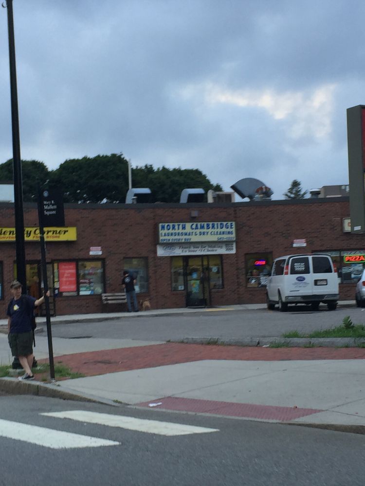 Brick storefront with North Cambridge Liquors, a white van, and people outside on a cloudy day.