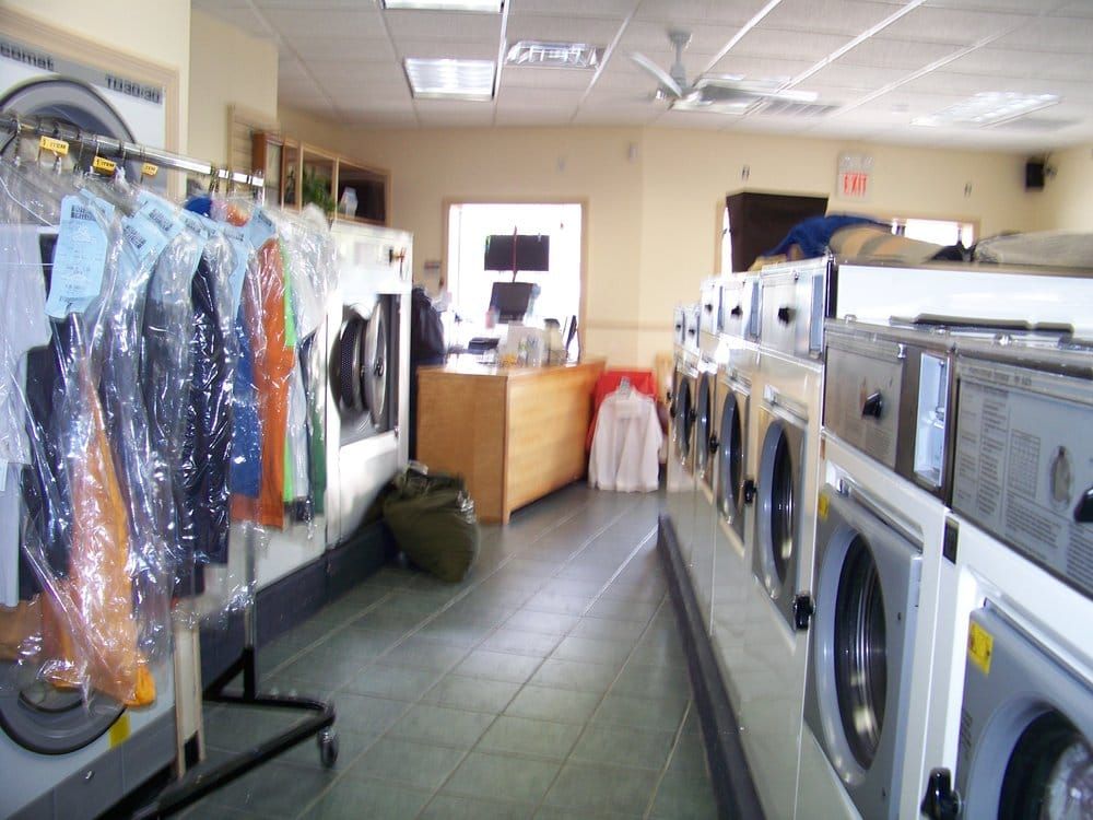 Dry cleaning business with machines, clothes on rack, and counter in the background.