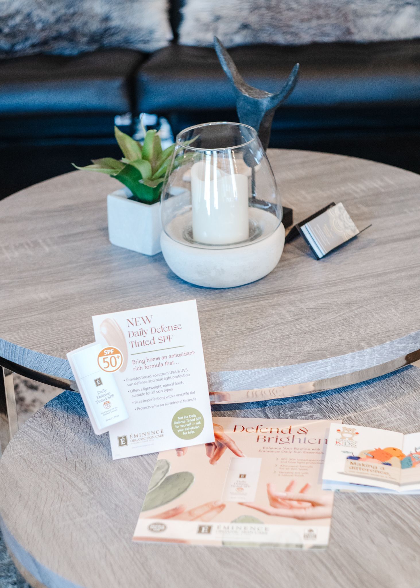 A round coffee table with a candle and brochures on it in a living room.