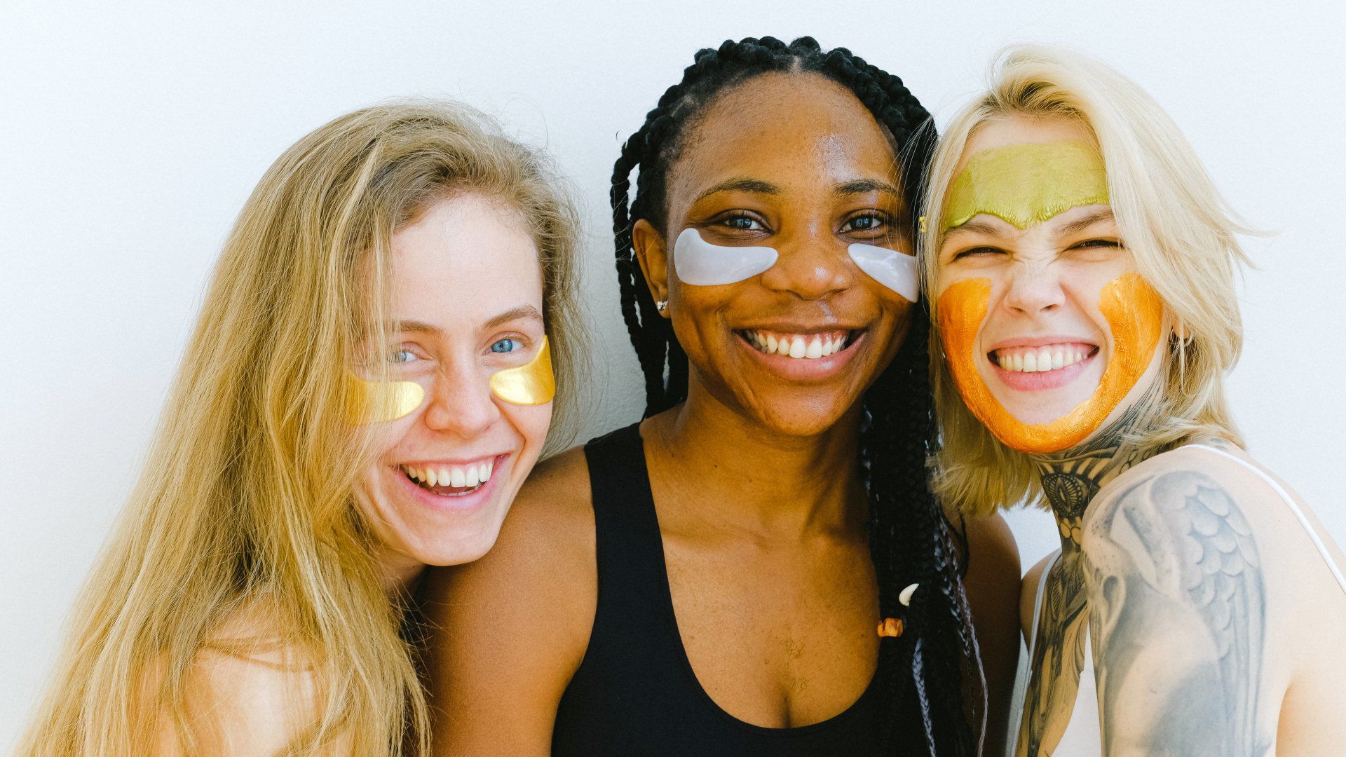 Three women wearing face masks are smiling for the camera.