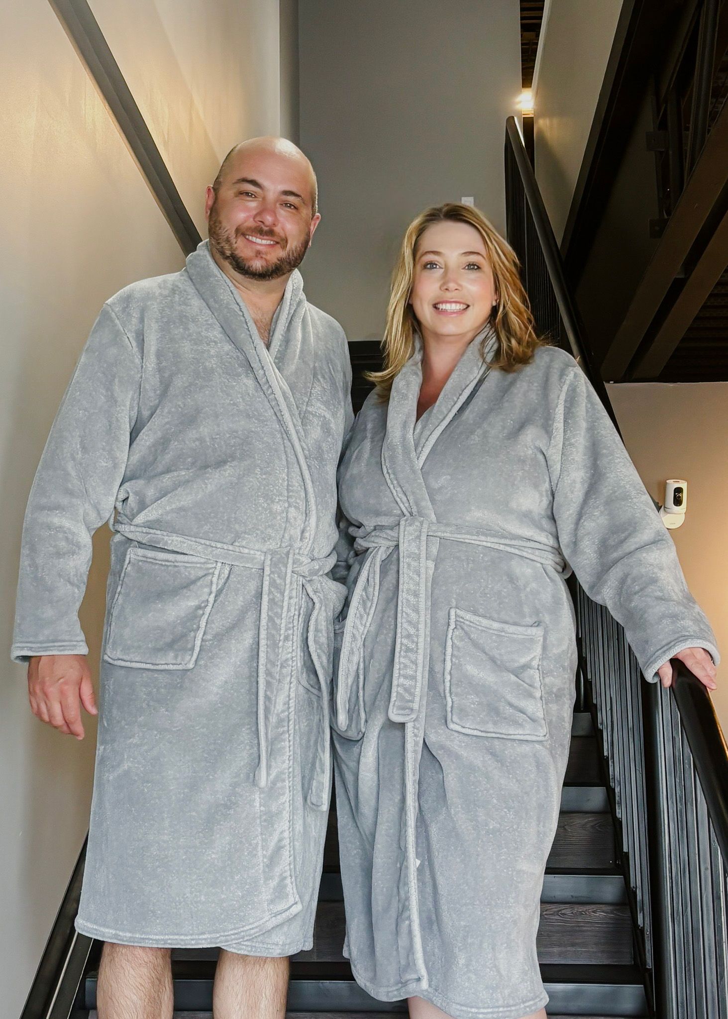 A man and a woman in bathrobes are standing next to each other on a set of stairs.