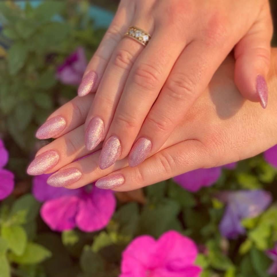 A close up of a woman 's hands with pink nails and a ring.