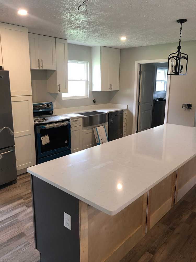 Modern kitchen with white cabinets, large island, stainless appliances, and light wood flooring