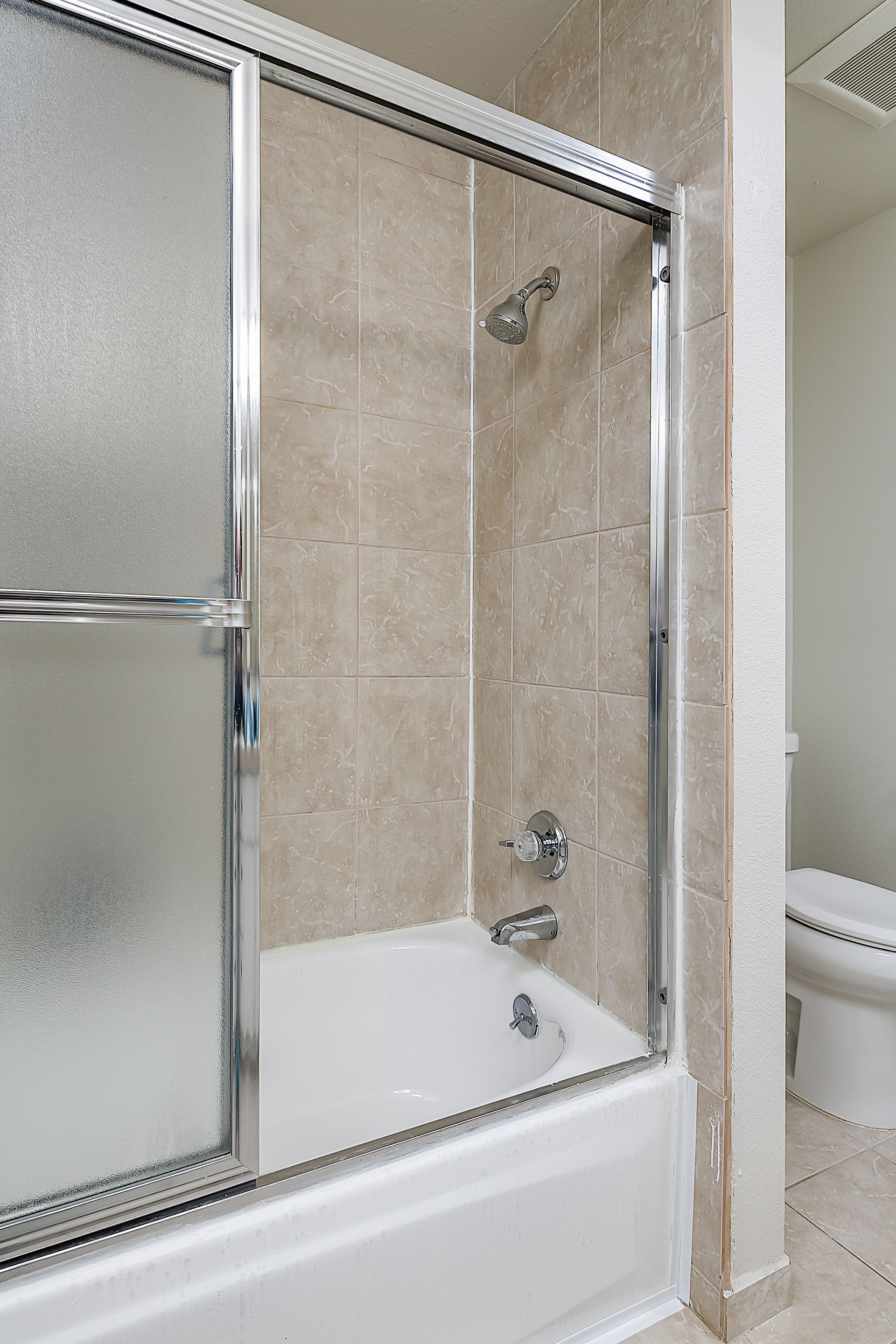 Photo showing a tub-shower combination, with sliding translucent doors