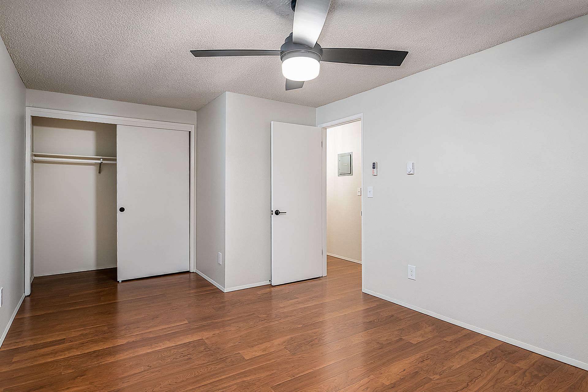 Photo showing a bedroom with a ceiling fan and sliding closet doors