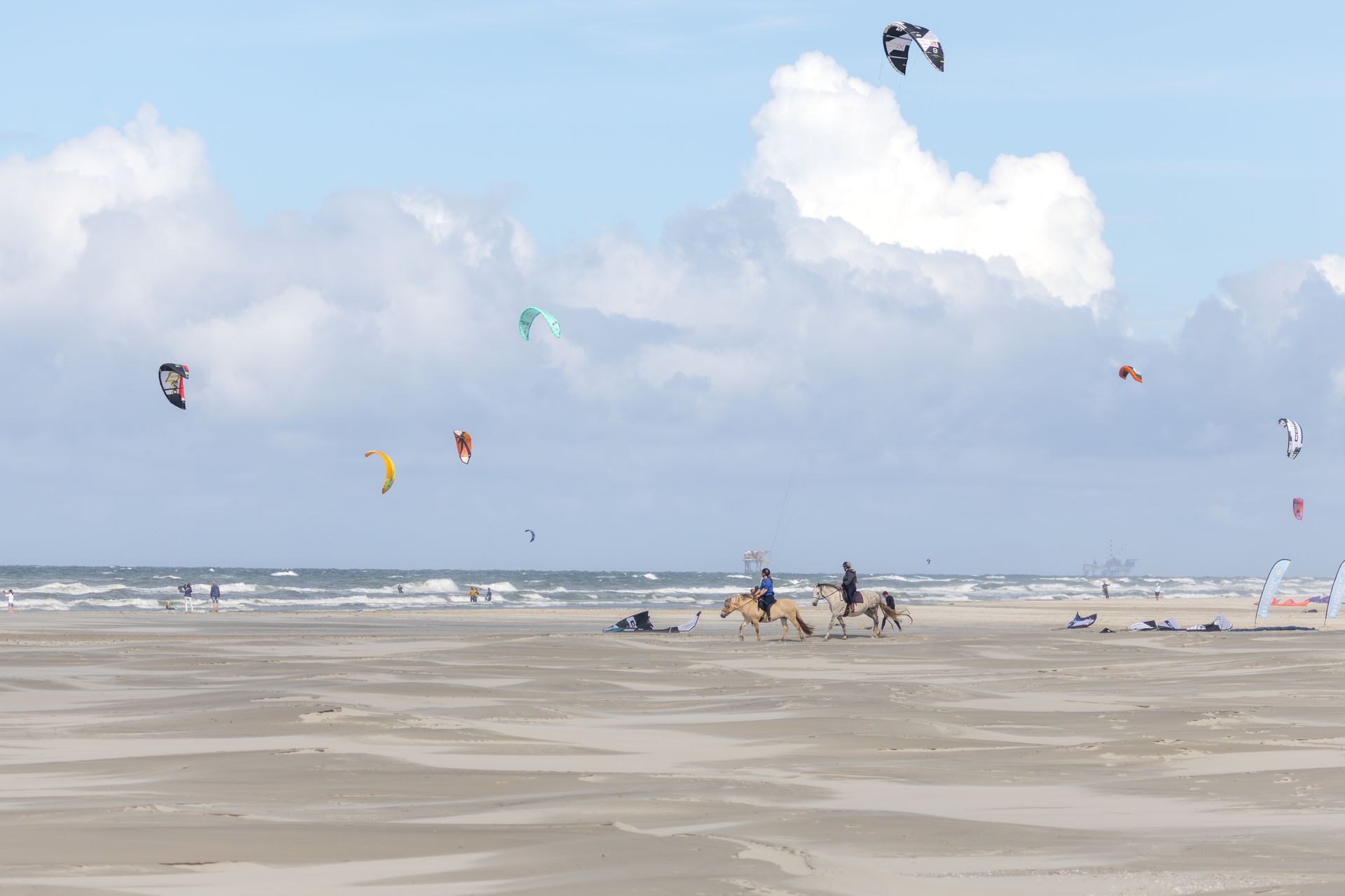 Ruiters (paardrijden) en kitesurfers (blowkarten) op het strand van Ameland.