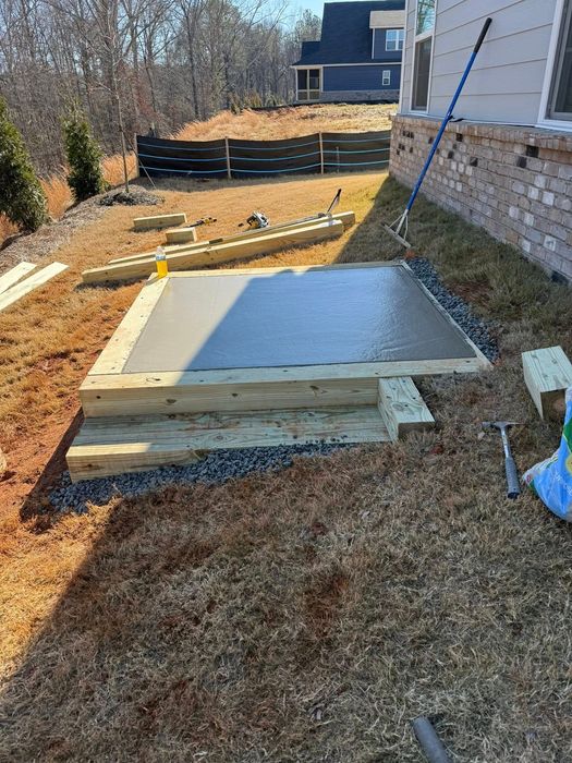 Concrete patio with wooden frame under construction outdoors.