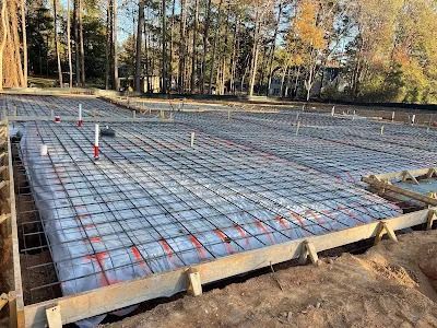 Construction site with rebar grid and wooden forms, ready for concrete pouring.