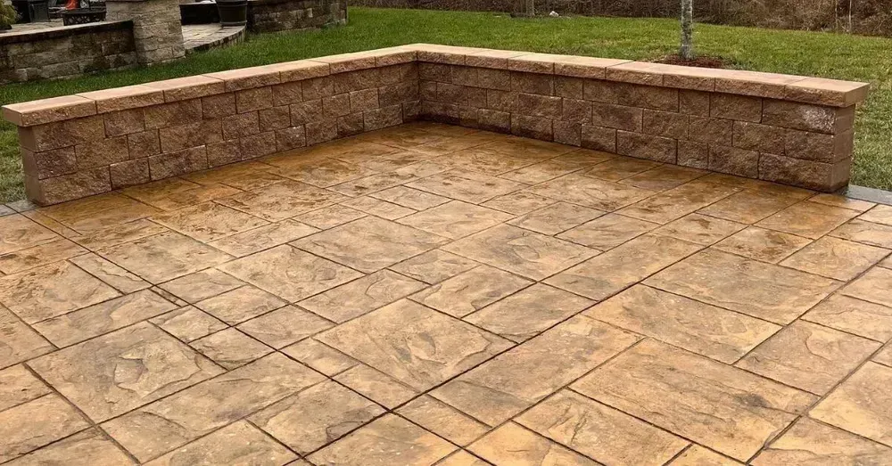 Stone patio with matching retaining wall in a yard.