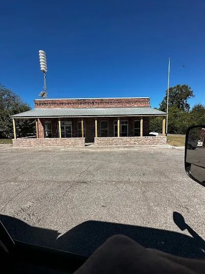 A one-story brick building with a porch under a bright blue sky.