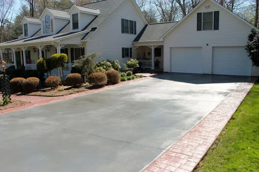 White house with gray driveway and red brick edging.