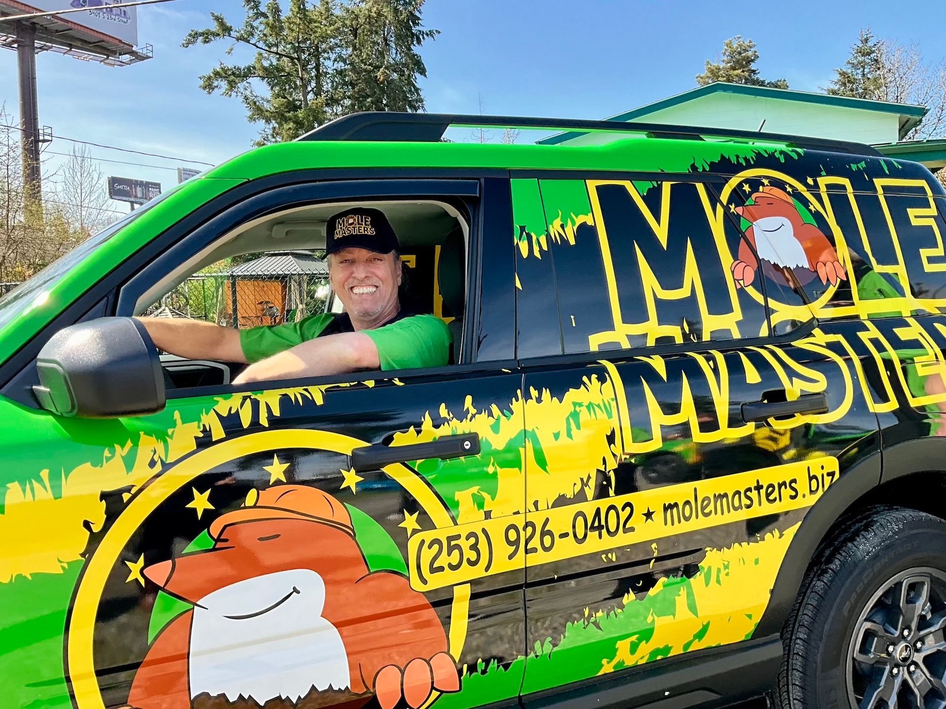 A man is sitting in the driver 's seat of a green and yellow van.