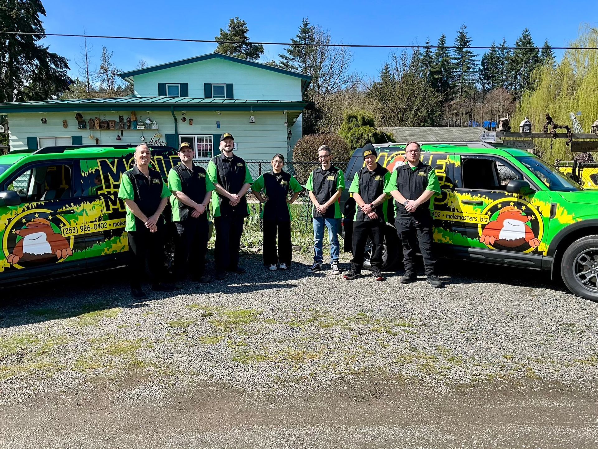 A group of people are posing for a picture in front of their trucks.