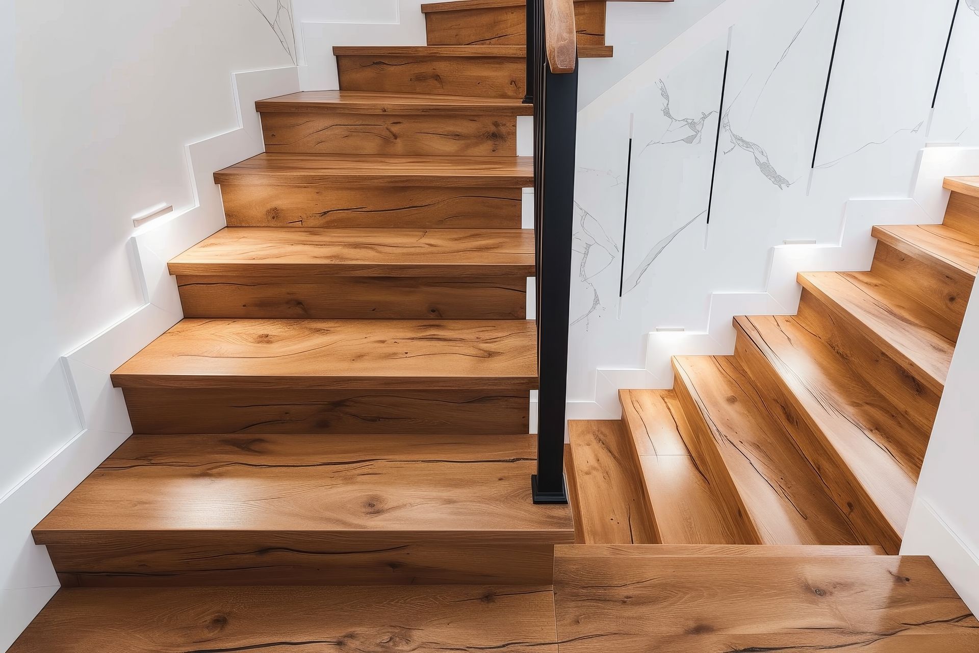A wooden staircase with a black railing in a house.