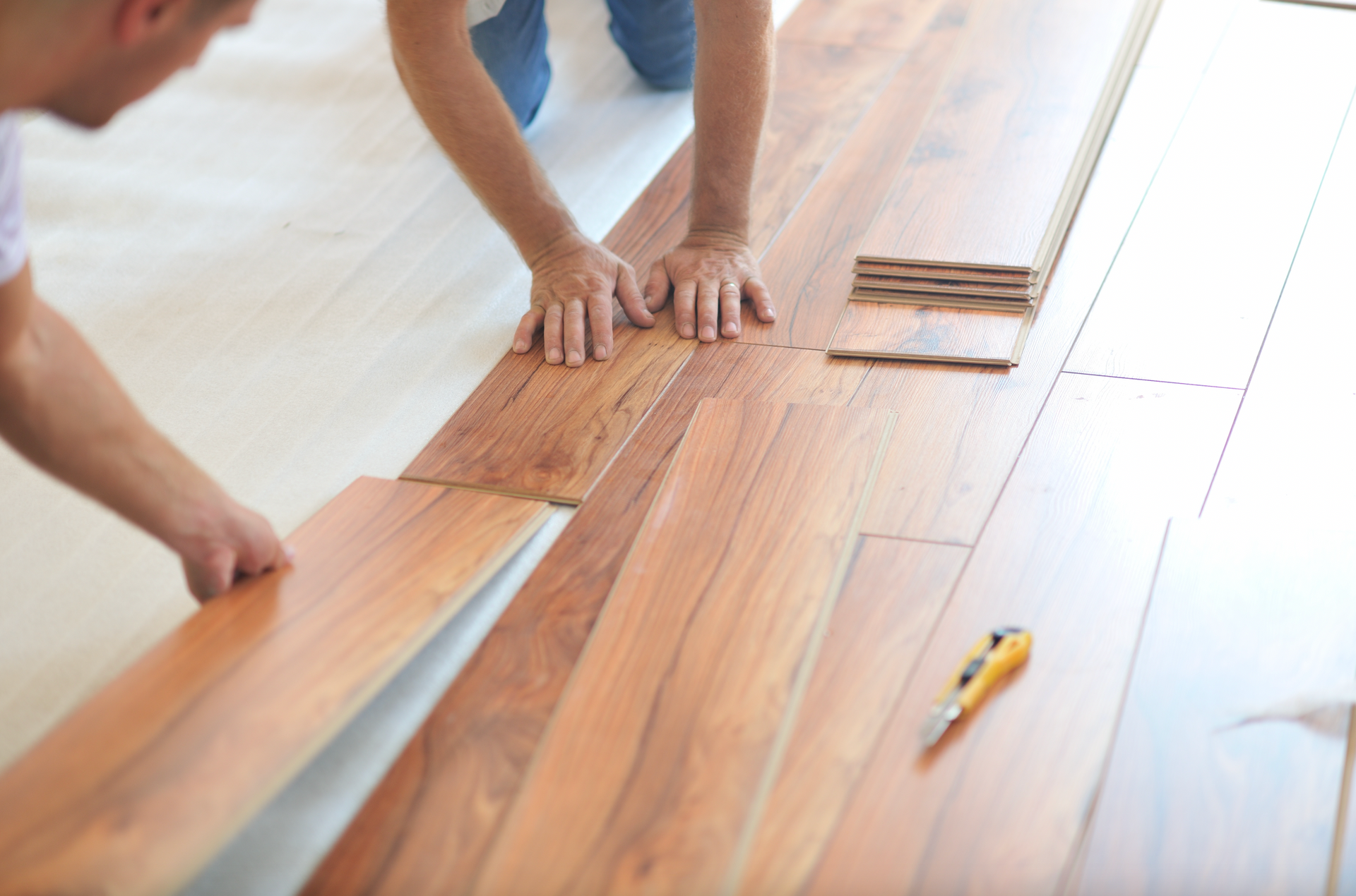 A man is installing a wooden floor in a room.
