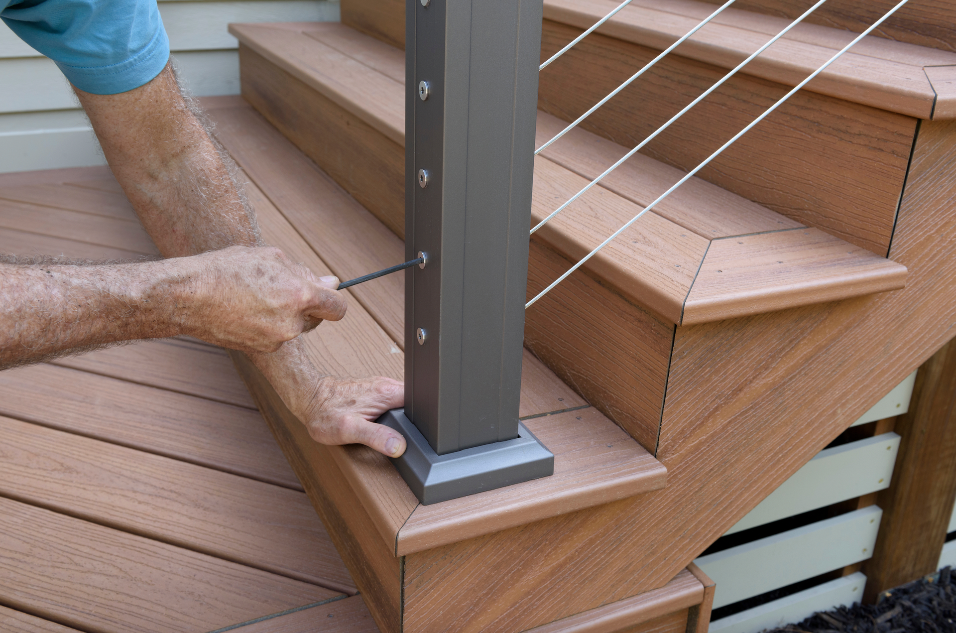 A man is installing a railing on a wooden deck.