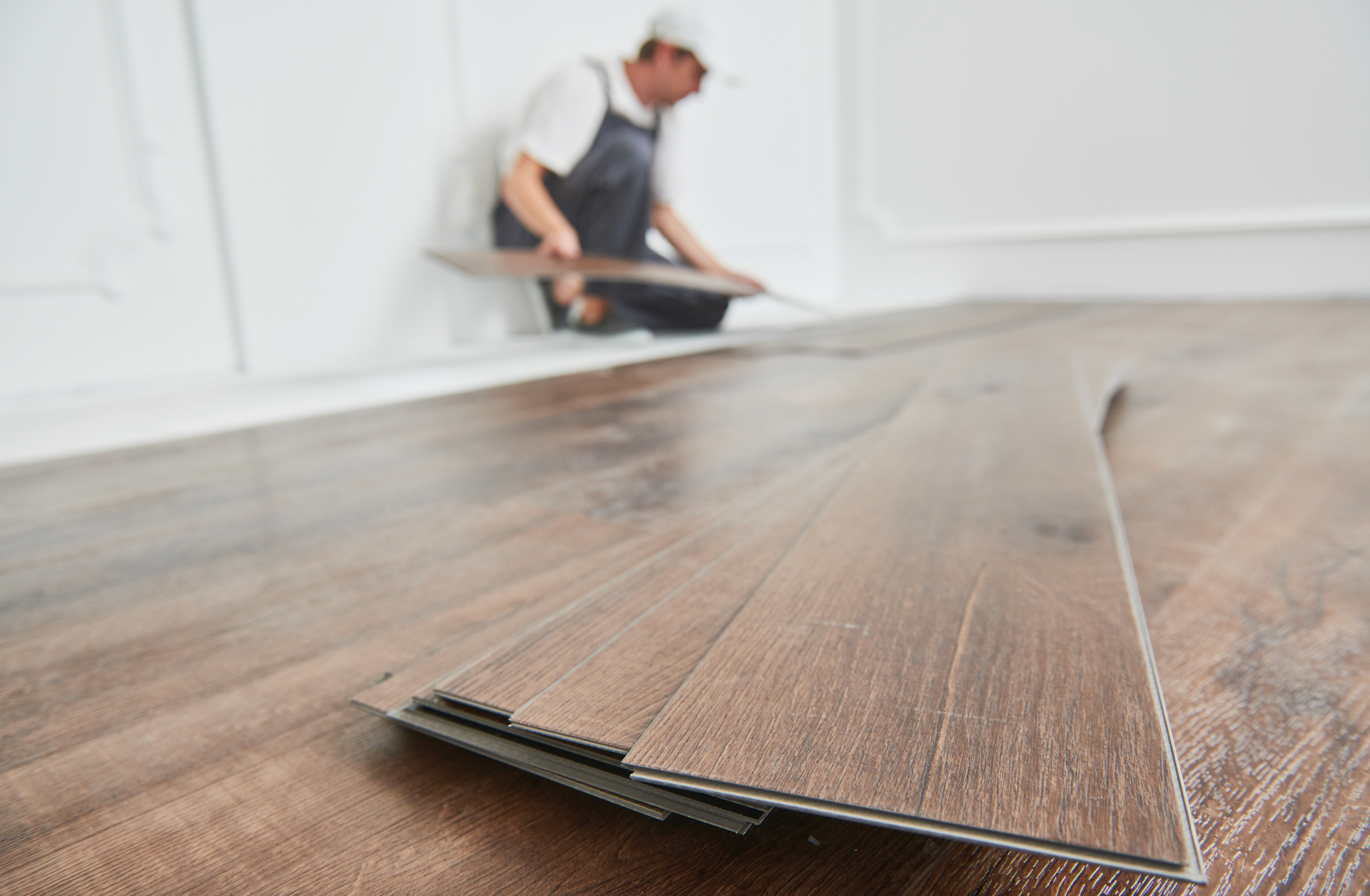 A man is installing a wooden floor in a room.