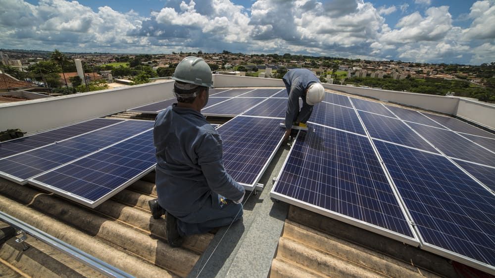 Two Men Are Installing Solar Panels On The Roof Of A Building — David Lewis Solahart in Ballina, NSW