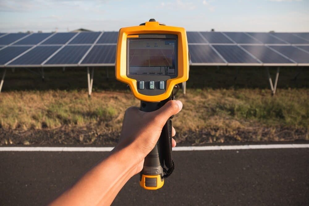 A Person Is Holding A Thermometer In Front Of A Field Of Solar Panels — David Lewis Solahart in Ocean Shores, NSW