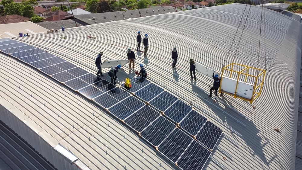 A Group Of People Are Installing Solar Panels On The Roof Of A Building — David Lewis Solahart in Murwillumbah, NSW