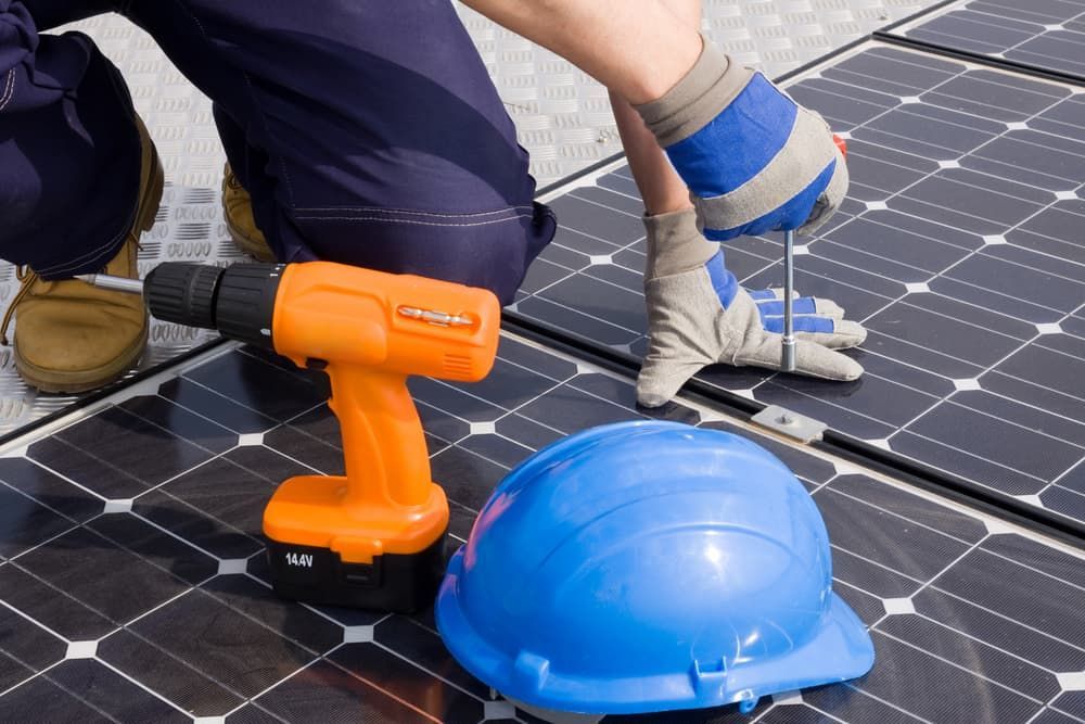 A Man Is Working On A Solar Panel With An Orange Drill And A Blue Hard Hat — David Lewis Solahart in Kingscliff, NSW