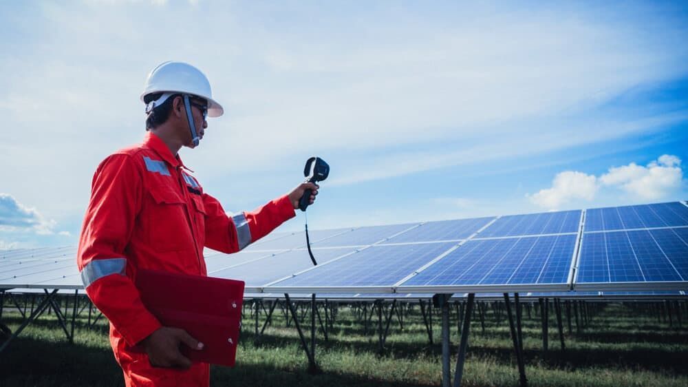 A Man Is Holding A Thermometer In Front Of A Solar Panel — David Lewis Solahart in Tenterfield, NSW