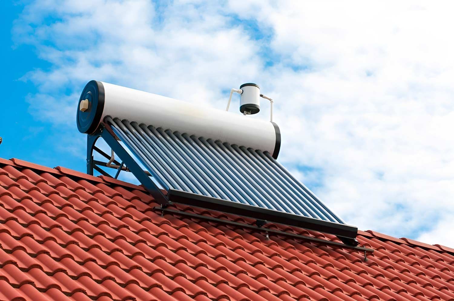 A Solar Water Heater Is Sitting On Top Of A Red Tiled Roof — Solahart In Goonellabah, NSW