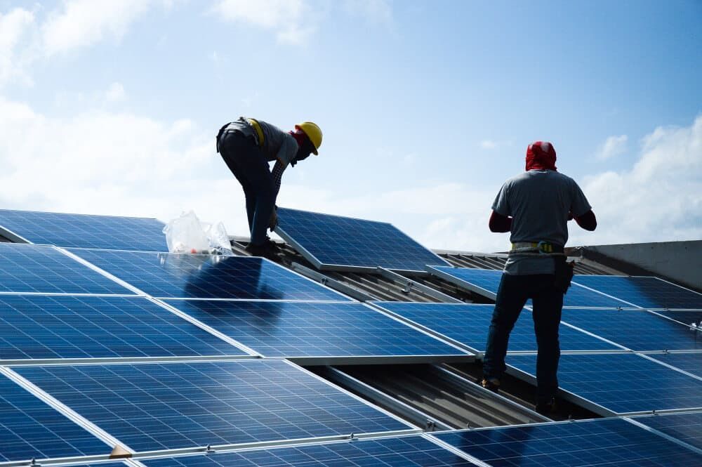 Two Men Are Installing Solar Panels On A Roof — David Lewis Solahart in Tenterfield, NSW