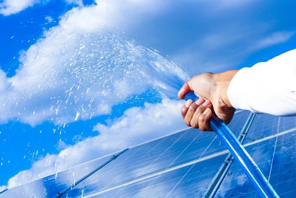 A Person Is Watering A Solar Panel With A Hose — David Lewis Solahart in Casino, NSW