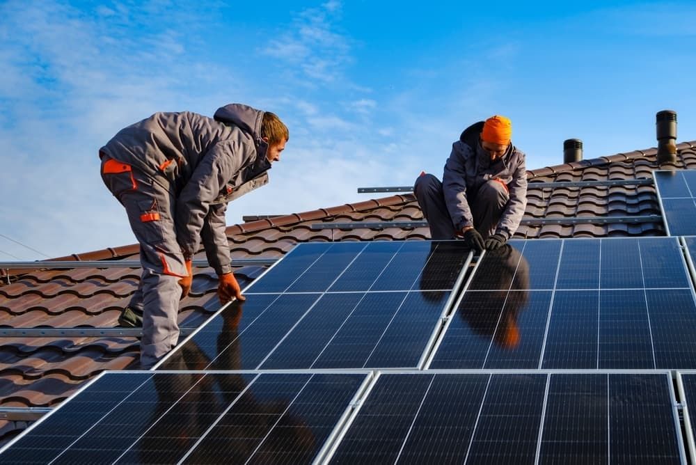 Two Men Are Installing Solar Panels On The Roof Of A House — David Lewis Solahart in Ocean Shores, NSW