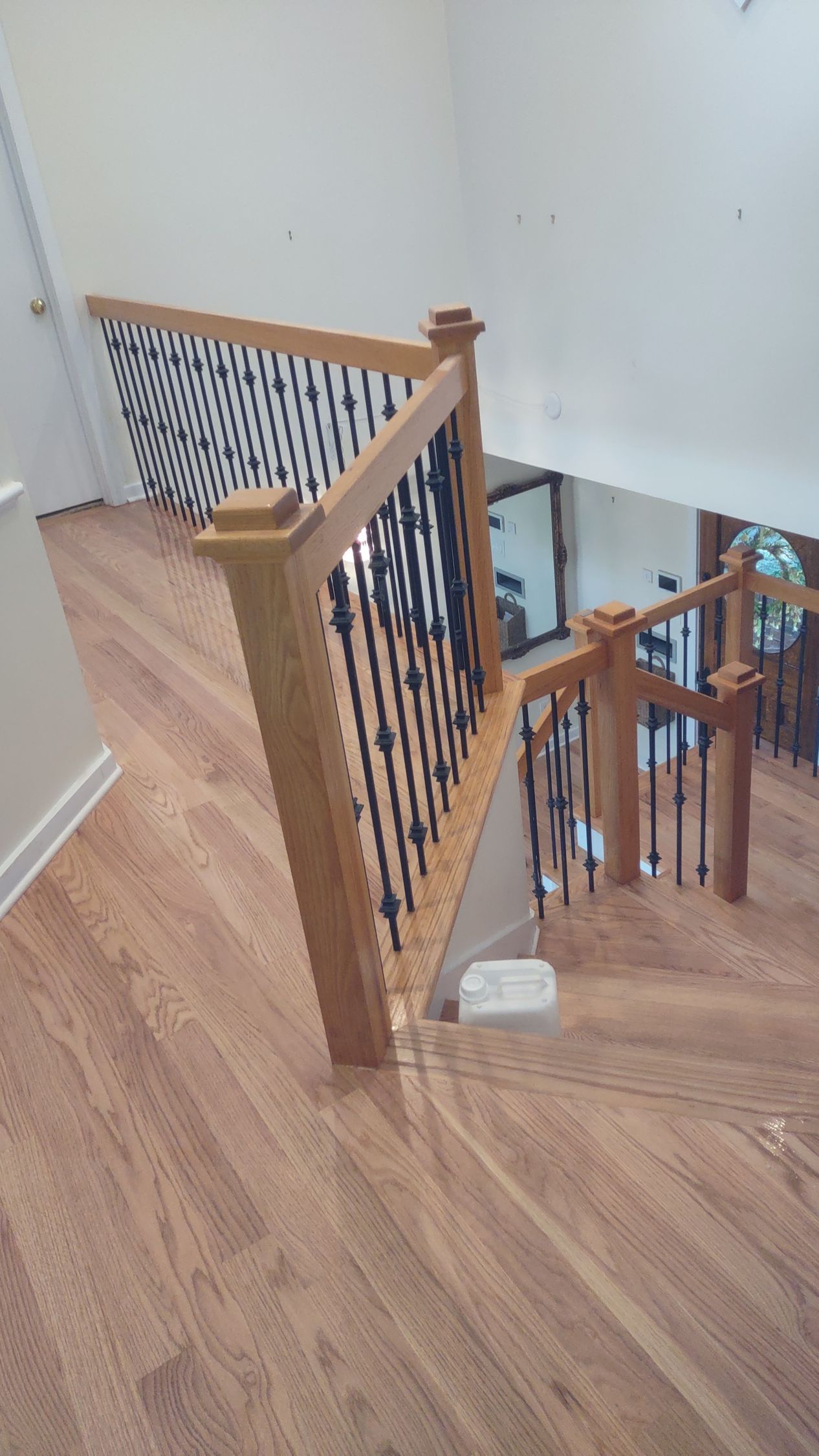 Wooden staircase with black metal balusters and light hardwood flooring.