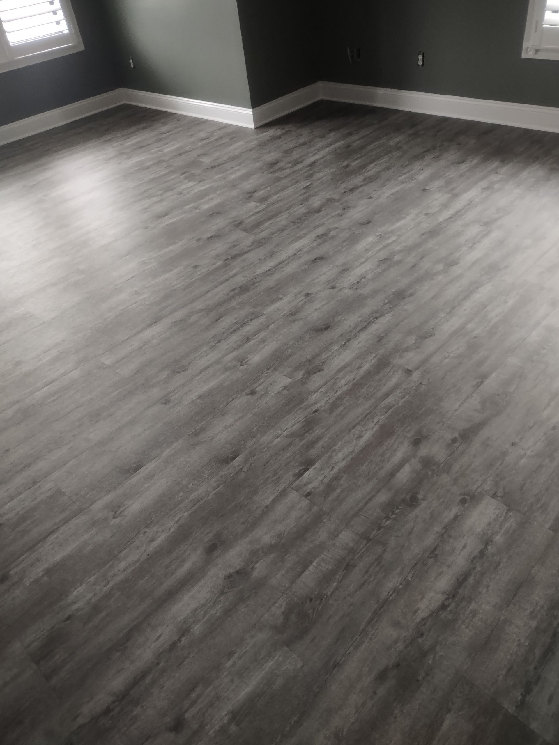 Gray wood-look flooring in a room with white trim and dark gray walls.