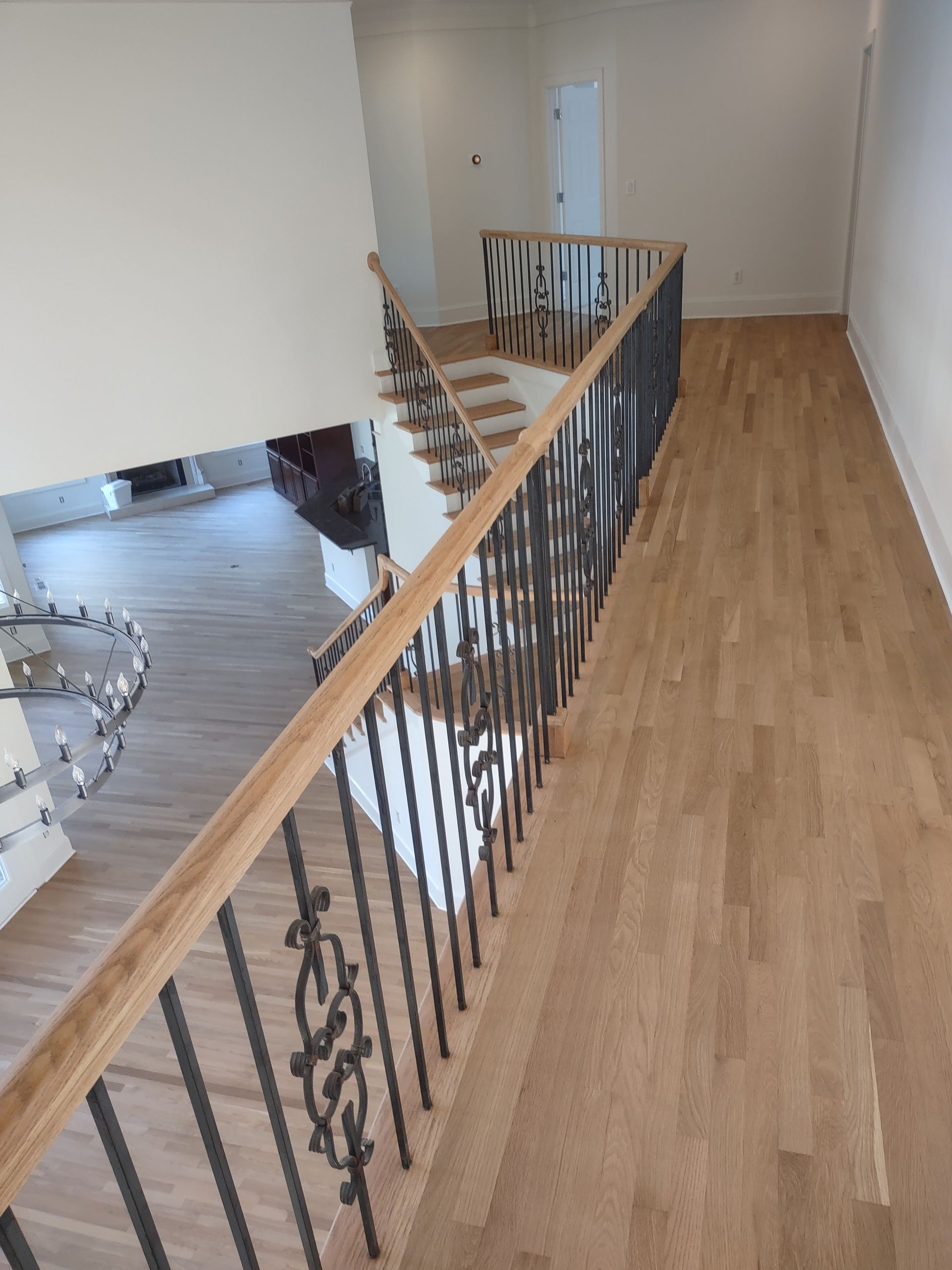 Wooden staircase with black metal railing, leading to an upper level with light wood floors.