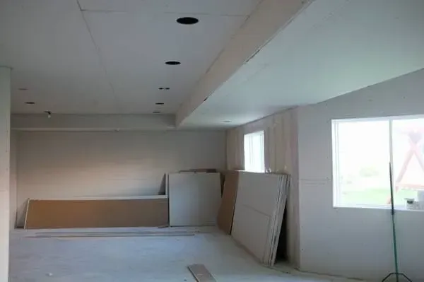 An empty room with a lot of drywall and windows