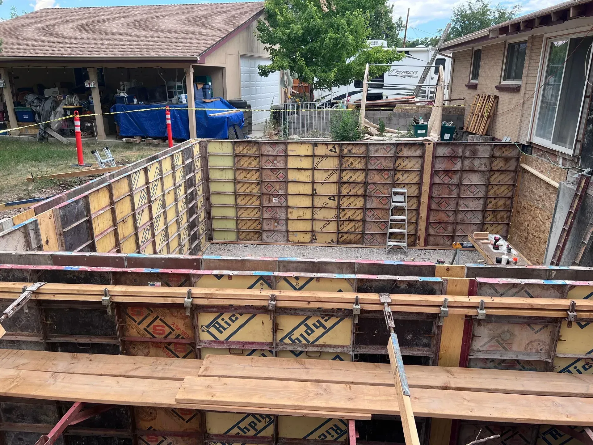 A swimming pool is being built in the backyard of a house.