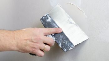 A person is plastering a wall with a spatula.