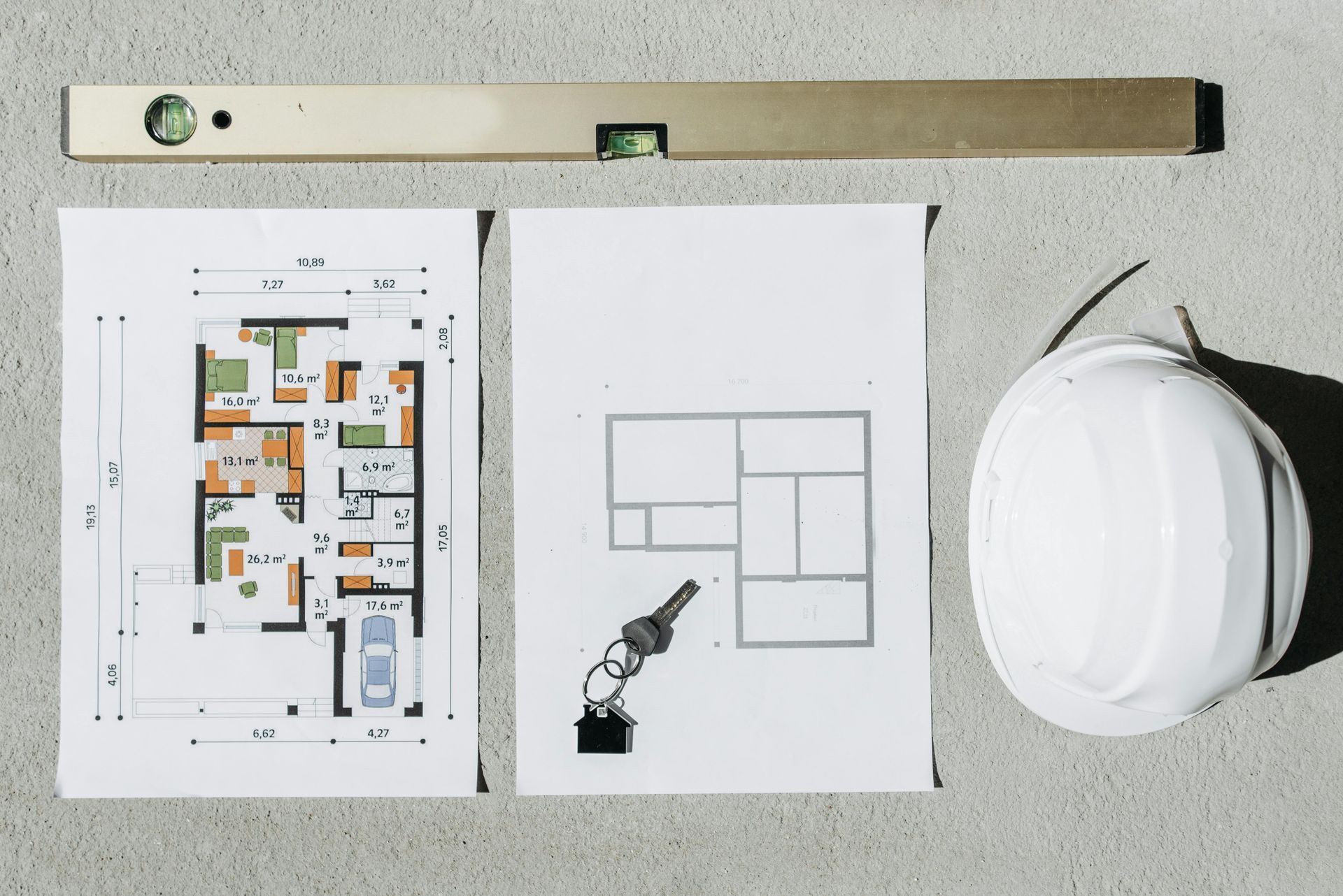 A drawing of a house , a level , and a hard hat are on a table.