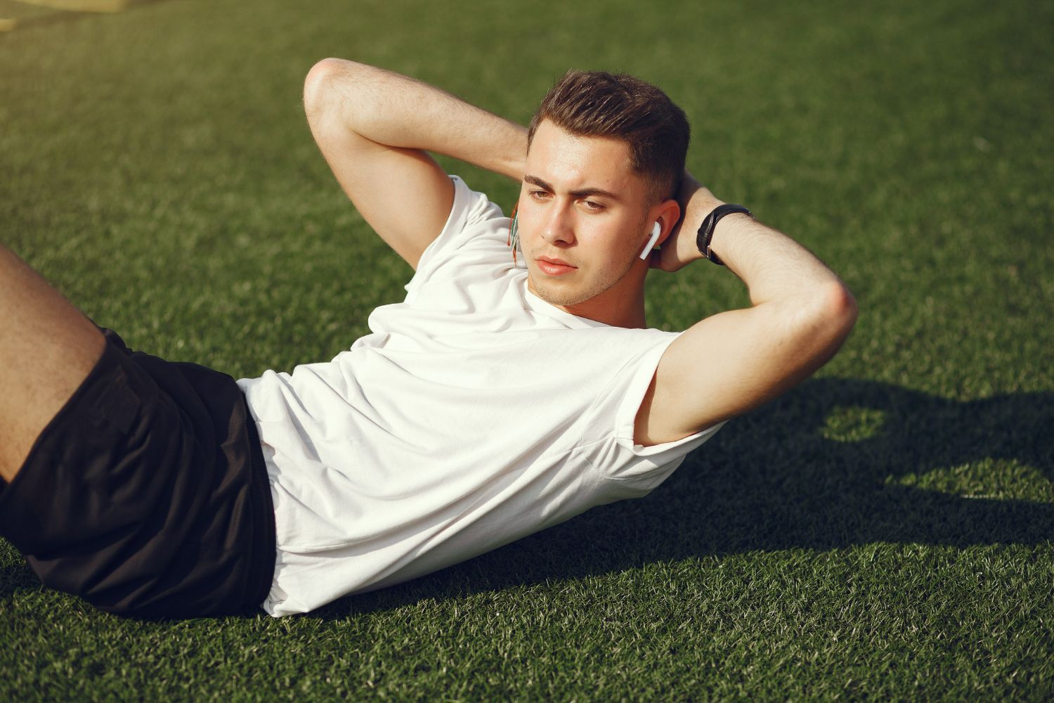 A young man is doing sit ups on the grass.