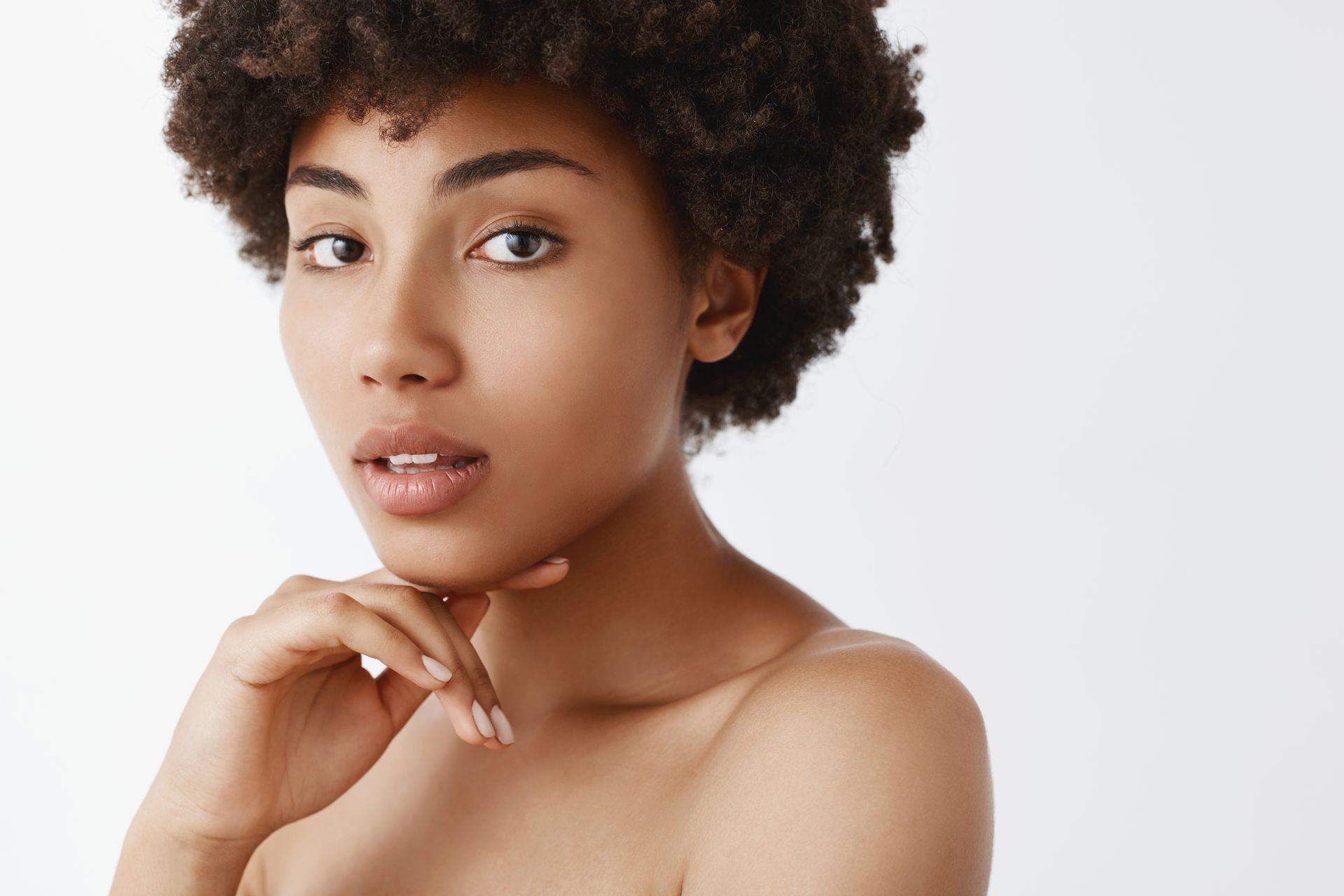 A woman is smiling and touching her face with her hands.